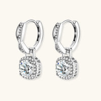 Sterling silver twisted hoop earrings with round moissanite stones in halo settings against neutral background.