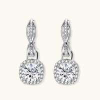 Sterling silver twisted hoop earrings with round moissanite stones in halo settings against neutral background.