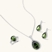 White gold plated jewelry set with green teardrop gemstones and cubic zirconia halos on cream background.