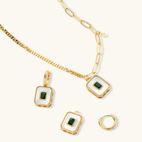 Gold-plated jewelry set with white enamel square pendants and emerald CZ stones on cream background.