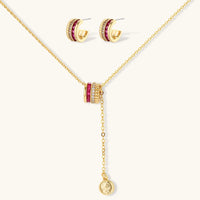 Three-piece jewelry set featuring 14K gold plated pieces with deep red cubic zirconia stones and clear crystals on cream background.