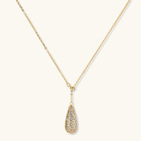 Gold-plated teardrop necklace and earrings covered in AAA cubic zirconia crystals on cream background.
