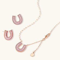 Sparkling horseshoe-shaped jewelry set with AAA cubic zirconia in gold-plated and white gold finishes on cream background.