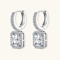 Sterling silver huggie hoops with emerald-cut moissanite drops featuring pavé-set crystals on white background.
