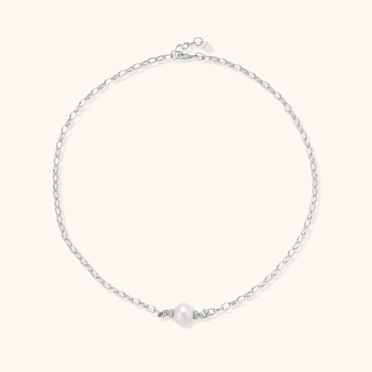 Dainty rhodium-plated silver chain necklace with centered 10mm freshwater pearl and crystal accents on cream background