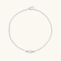 Dainty rhodium-plated silver chain necklace with centered 10mm freshwater pearl and crystal accents on cream background