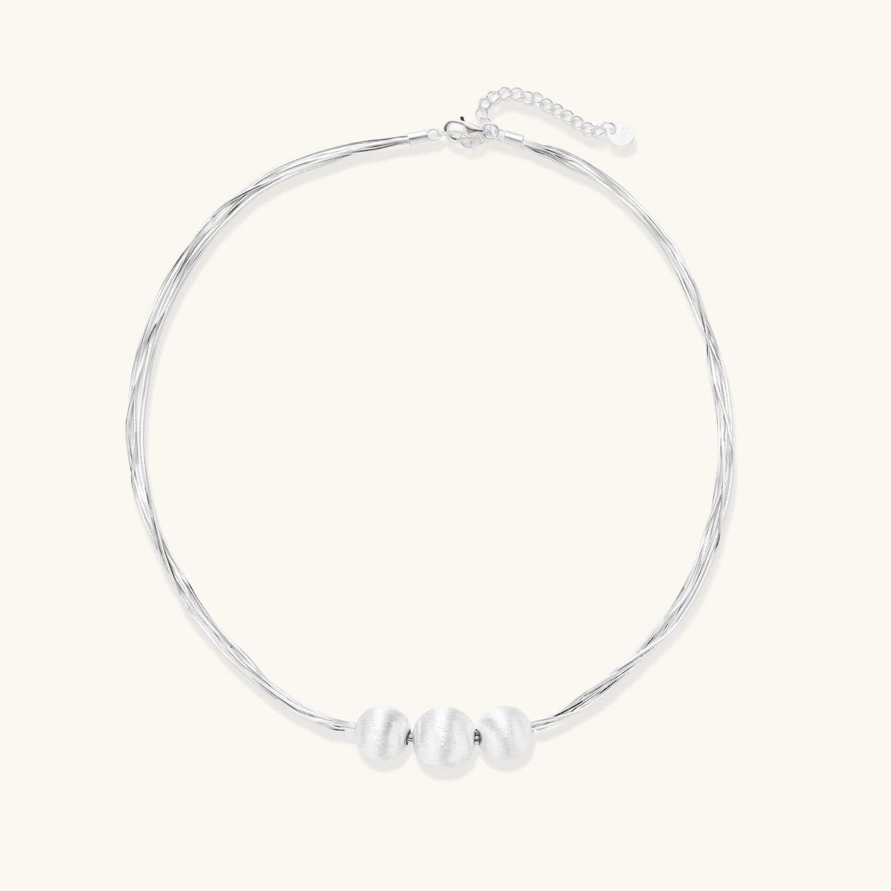 Sterling silver multi-strand necklace with three brushed round beads on cream background