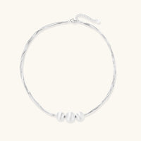 Sterling silver multi-strand necklace with three brushed round beads on cream background