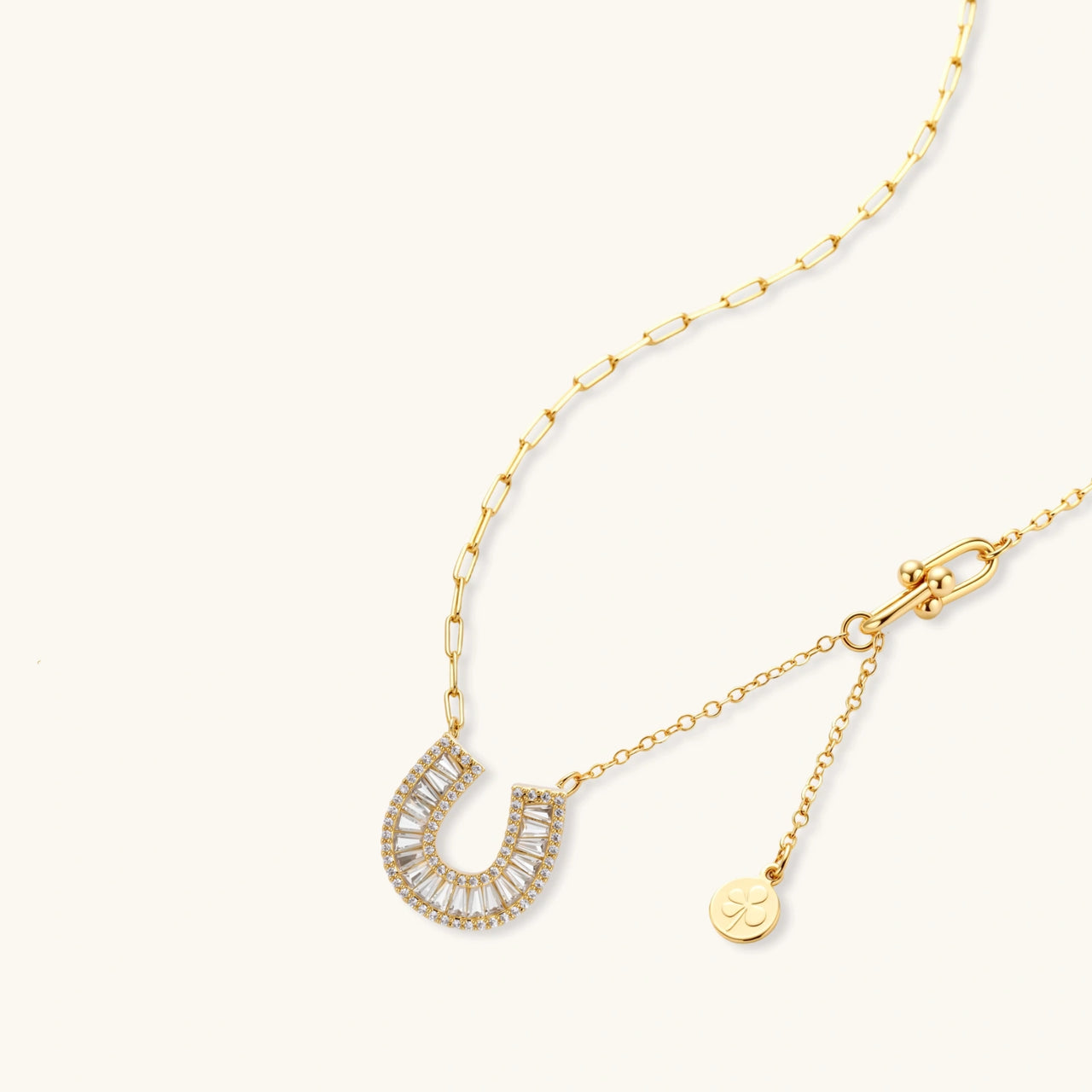 Gold-plated horseshoe necklace and earring set with baguette and round crystals arranged in geometric pattern on white background.