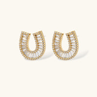 Gold-plated horseshoe necklace and earring set with baguette and round crystals arranged in geometric pattern on white background.