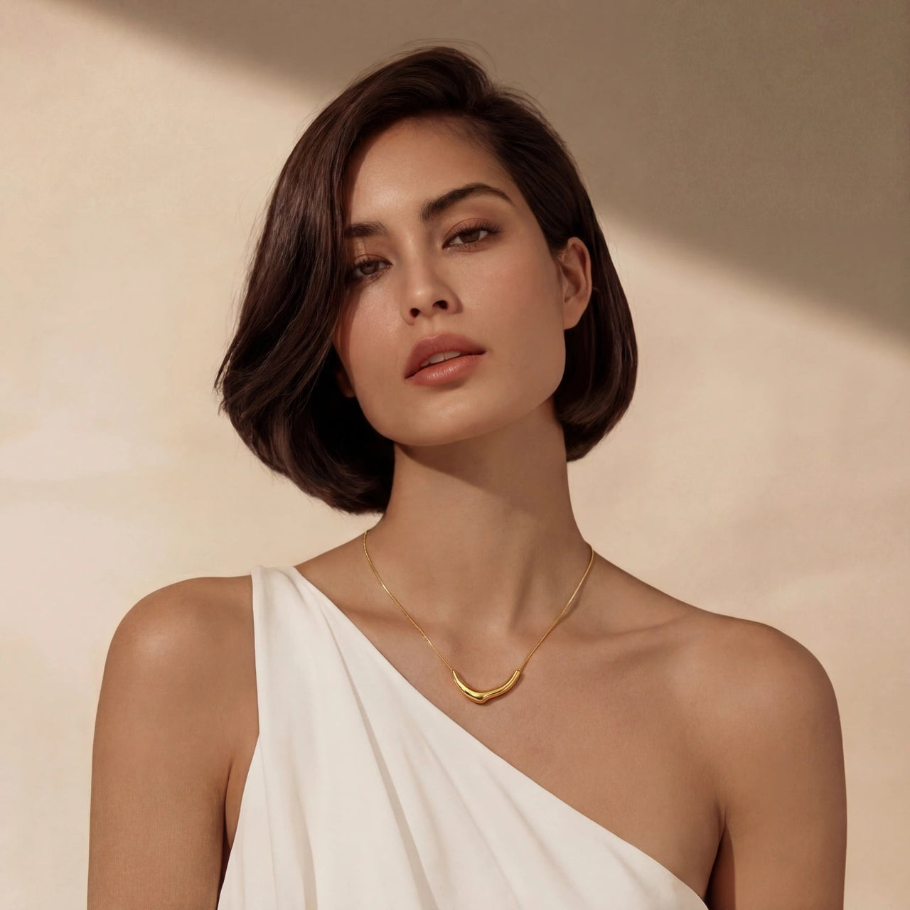 A model wearing a Curve Statement Necklace, featuring a sleek curved gold-plated pendant against a neutral background.