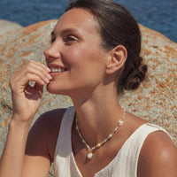 Golden Leaf Baroque Necklace featuring freshwater pearls and gold-plated leaves worn by a woman outdoors.