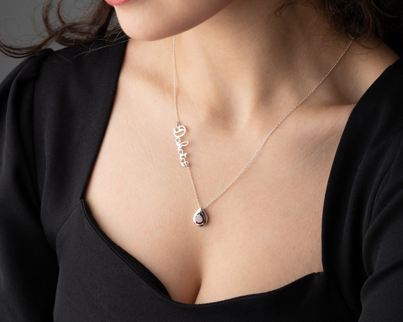 Personalized Cursive Name & Birthstone Necklace worn by a woman, featuring a silver cursive name and a gemstone.