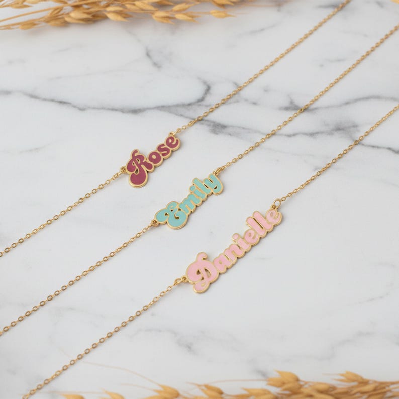 Personalized Cursive Name Necklace displayed in three styles: Rose, Emily, and Danielle on a marble background.