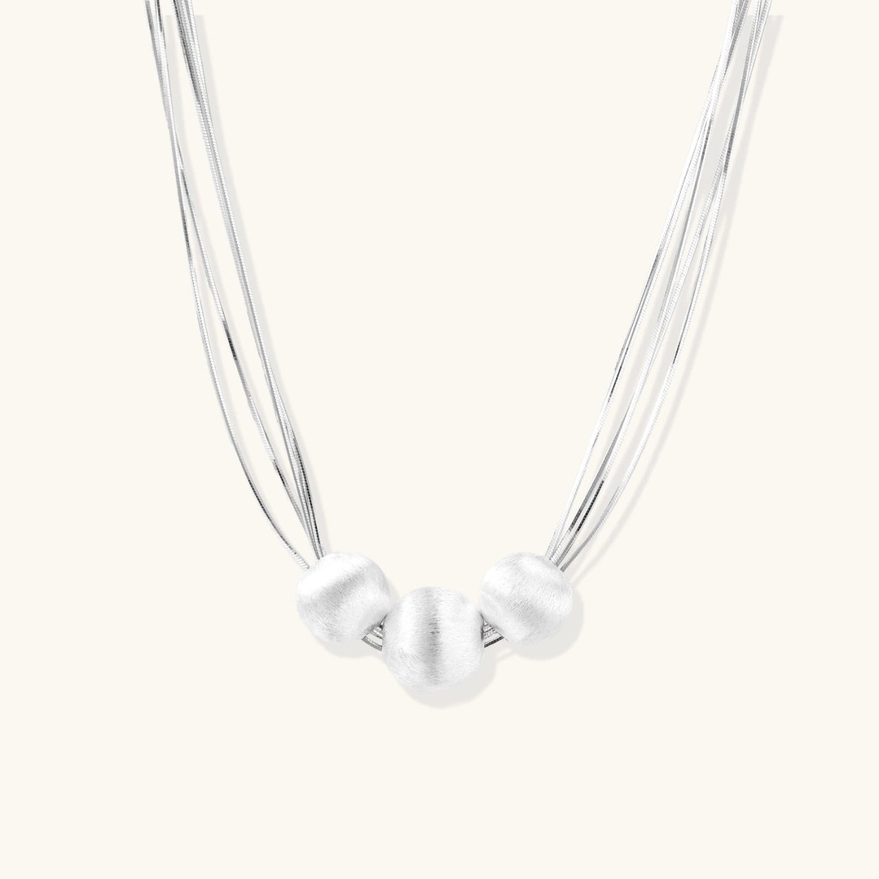 Silver Strand Layers Necklace featuring three brushed sterling silver beads and delicate multi-strand chains.